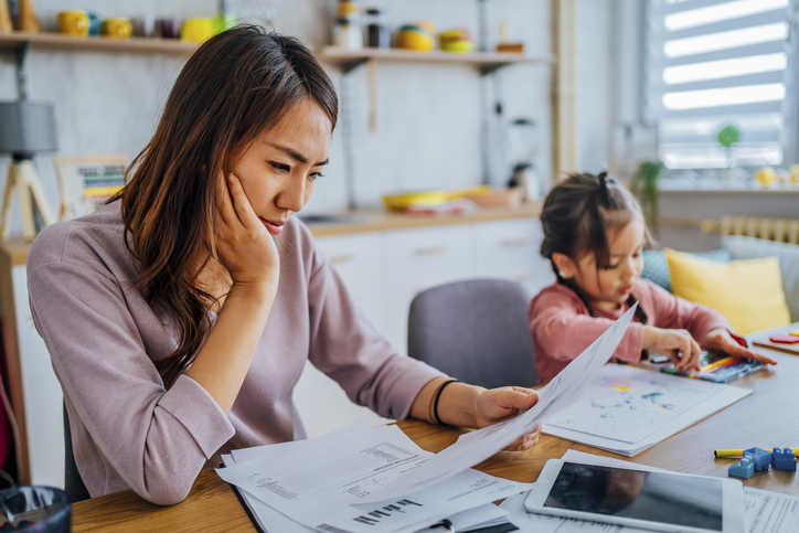 A women and a young child sitting at the table looking over bills.