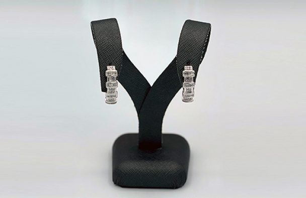 A pair of earrings on display with a grey background.