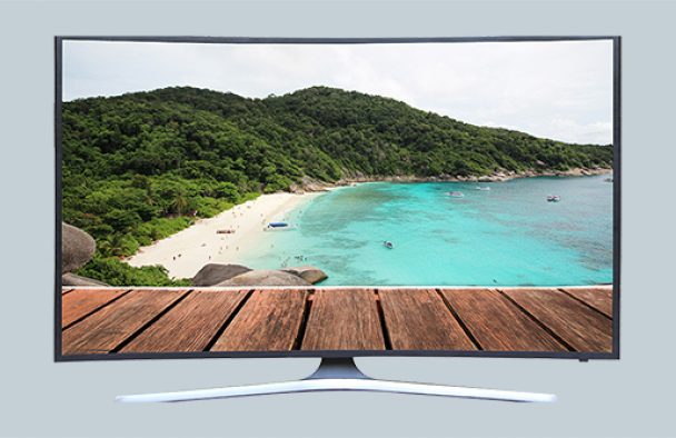 A large TV with a tropical screen saver on display with a grey background.