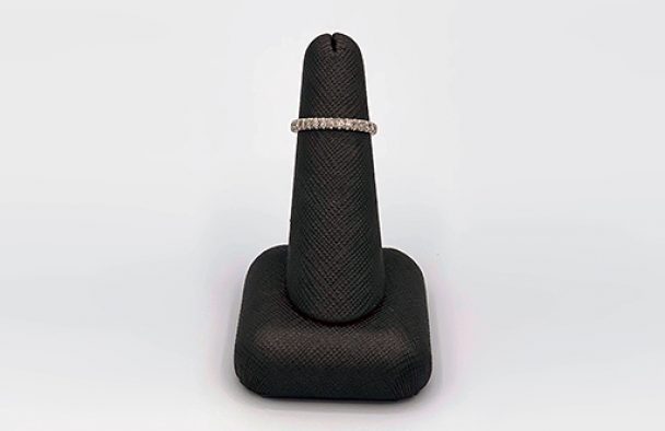 A wedding ring on display with a grey background.